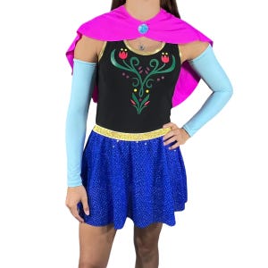May include: A blue and black dress with a sparkly blue skirt and a pink cape. The dress features a floral design on the bodice.