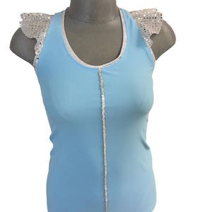 May include: A light blue sleeveless top with a silver trim around the neckline and a silver sequined strip down the center. The top has silver sequined ruffle sleeves.