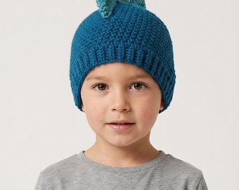 May include: A dark teal crochet beanie featuring a ribbed brim and three upright, triangular spikes in a lighter teal shade attached to the top. The hat is constructed with a textured yarn stitch pattern, providing a structured and fitted appearance.