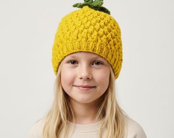 May include: A bright yellow crochet beanie featuring a textured, diamond-like stitch pattern that mimics the skin of a pineapple. The hat is topped with a cluster of green crocheted leaves that stand upright, creating a distinct pineapple-shaped design.