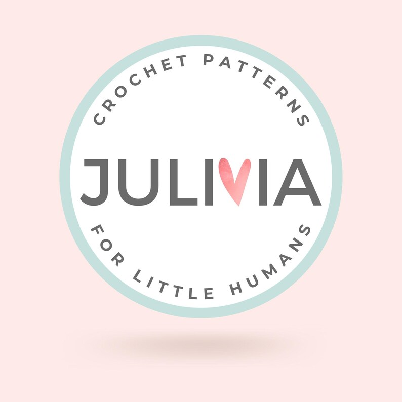Peut inclure: Logo circulaire avec l'inscription "CROCHET PATTERNS" et "FOR LITTLE HUMANS" dans un cercle bleu clair. Le mot "JULIVIA" est au centre, avec un c&oelig;ur aquarelle rempla&ccedil;ant la lettre "I". Fond rose clair.