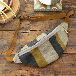 Peut inclure: Une banane rayée marron, verte et beige avec une fermeture à glissière et une sangle réglable marron.