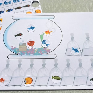 Może przedstawiać: Kolorowa gra edukacyjna z ilustracjami ryb. Gra zawiera scenę akwarium z naklejkami z rybami, a także dodatkowe naklejki z rybami w workach i siatkę do dopasowywania. Ryby są w odcieniach niebieskiego, pomarańczowego, czerwonego i czarnego.