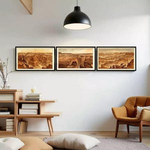 Puede incluir: Tres grabados enmarcados que representan un paisaje de cañón en tonos marrones y beige. Los grabados se exhiben en una pared blanca, encima de una mesa auxiliar de madera y un sillón color mostaza. Una lámpara colgante negra cuelga del techo.