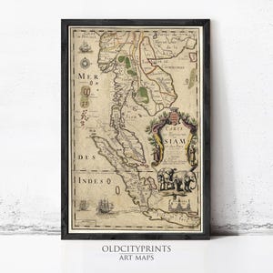 Op de afbeelding: Ingelijste vintage kaartprint van Siam en de Indië, met gedetailleerde cartografie, nautische elementen en decoratieve illustraties. De kaart zit in een zwart frame, met de tekst "OLD CITY PRINTS ART MAPS" onderaan.