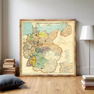 May include: A framed vintage map of Germany, featuring a detailed depiction of the country's administrative divisions. The map is in a wooden frame and has a faded, antique appearance with various colors highlighting different regions. The text on the map is in Russian.