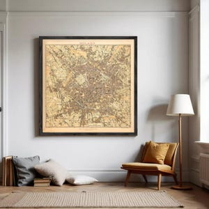 Op de afbeelding: Een grote, vierkante, ingelijste kaart van Milaan in vintage-stijl met gedetailleerde stratenplannen, stadswijken en geografische kenmerken in tinten beige, bruin en oker, met het woord MILANO in het zwart bovenaan in het midden gedrukt.