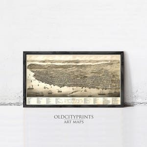 May include: A framed vintage map print of a city, showing detailed streets, buildings, and waterways. The sepia-toned artwork includes small ships and the text "OLDCITYPRINTS ART MAPS" at the bottom. The map is encased in a black frame.