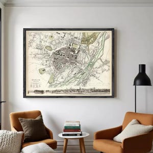 Puede incluir: Mapa antiguo enmarcado de Múnich, Alemania, en blanco y negro con detalles en verde y beige. El mapa es detallado, mostrando calles, edificios y el río Isar. El mapa está en un marco negro.