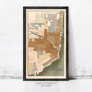 May include: Framed vintage map of Miami, Florida, in a black frame. The map features a detailed layout of the city with various colors highlighting different areas. The text "THE OFFICIAL PLAT CITY OF MIAMI" is visible.