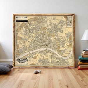 Puede incluir: Un mapa antiguo enmarcado de Colonia, Alemania, en tonos sepia. El mapa, titulado "PLAN von KÖLN", muestra el diseño de la ciudad, incluido el río Rin. El marco de madera complementa la estética antigua del mapa, adecuado para la decoración del hogar.