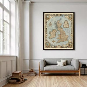 May include: A framed vintage-style map of the British Isles featuring a light blue ocean background, tan landmasses, and an ornate border decorated with small portraits and illustrations, all enclosed in a simple black rectangular frame.