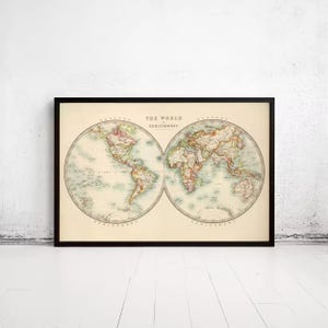 May include: A framed vintage-style map print titled The World in Hemispheres, featuring two circular projections of the Earth with muted pastel landmasses and pale blue oceans on a cream-colored background, enclosed in a thin black frame.