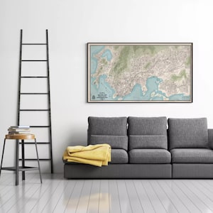 a gray couch with a yellow blanket draped over it, and a large framed map of a city hanging on the wall above the couch.