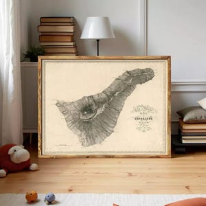 Peut inclure: Une carte vintage encadrée de Tenerife, îles Canaries, dans un cadre en bois. La carte est en noir et blanc, avec des détails topographiques. Le cadre est de couleur marron chaud, et la carte est exposée dans une pièce avec une lampe et des livres.