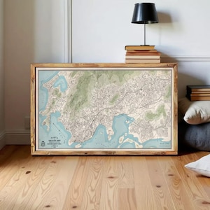 a large framed map of a city or region, with a wooden floor and a lamp in the background.