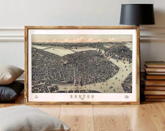 May include: A framed vintage map of Boston, Massachusetts, in sepia tones. The map, with the word "BOSTON" at the bottom, is set in a wooden frame and displayed on a wooden floor. A black lamp and books are visible.