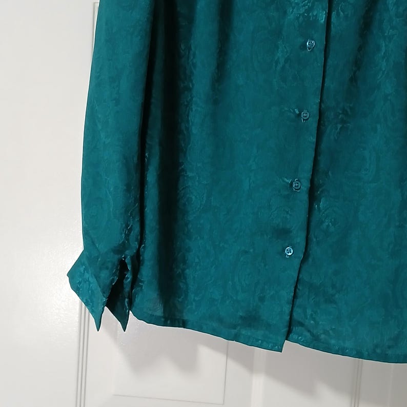 Peut inclure: Chemise boutonn&eacute;e de couleur sarcelle avec un motif cachemire subtil. Le chemisier &agrave; manches longues pr&eacute;sente des fermetures &agrave; boutons et un col classique. Le tissu a un l&eacute;ger &eacute;clat.