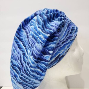 May include: Blue and white patterned surgical scrub hat with a wave design. The hat is made of a soft, comfortable fabric and is ideal for nurses, doctors, and other healthcare professionals.