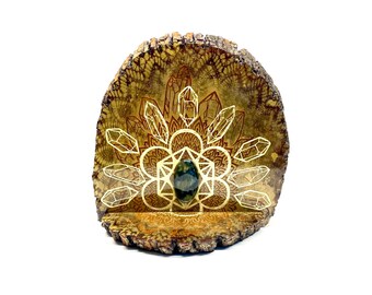 May include: A wooden slice with a geometric design and crystals, featuring a green gemstone in the center.