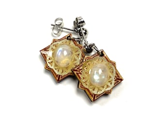 May include: A pair of gold and red star-shaped earrings with a moonstone center. The earrings have a silver hook closure.