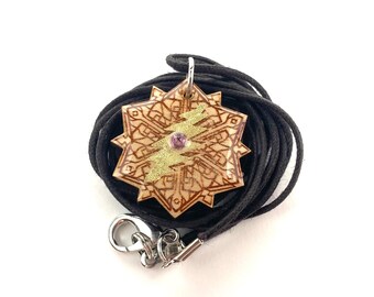 May include: A wooden pendant with a geometric design and a gold lightning bolt. The pendant is attached to a black cord with a silver clasp.