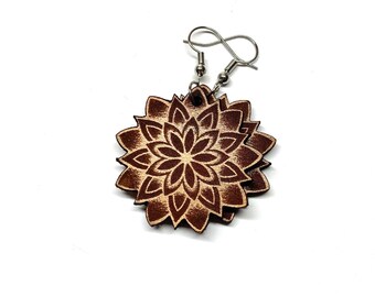 May include: A pair of wooden earrings with a brown mandala design. The earrings are made of wood and have a silver hook.