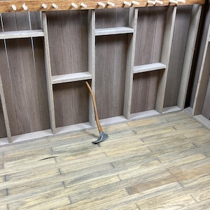 May include: A wooden wall with shelves and a wooden handle axe leaning against the wall.