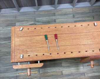 May include: A wooden workbench with two screwdrivers, one green and one red, lying on the surface. The workbench has a vise and a wooden handle.