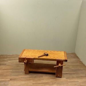 May include: A wooden workbench with a shelf and two vises. A small wooden mallet is on the workbench.