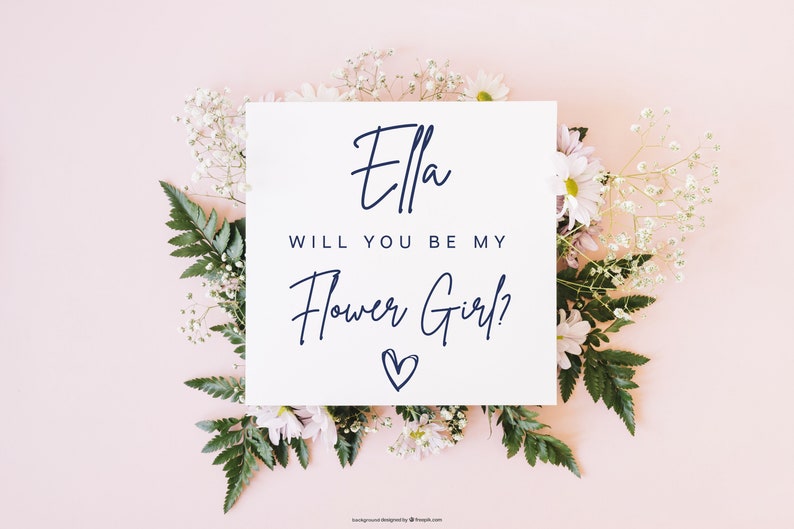 Pode incluir: Um cart&atilde;o branco com o texto "Ella, voc&ecirc; quer ser minha dama de honra?" em escrita cursiva azul marinho com um pequeno cora&ccedil;&atilde;o desenhado abaixo do texto. O cart&atilde;o est&aacute; rodeado de flores brancas e folhas verdes sobre um fundo rosa claro.