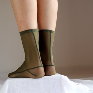 May include: A pair of olive green sheer socks with a seam down the back of the leg.