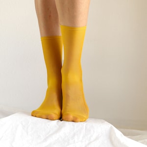 May include: A pair of bright yellow sheer socks. The socks are made of a thin, stretchy material and have a subtle sheen.