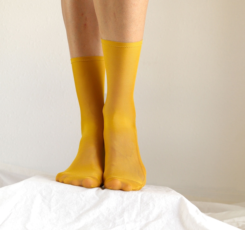 May include: A pair of bright yellow sheer socks. The socks are made of a thin, stretchy material and have a subtle sheen.