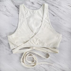 Peut inclure: Soutien-gorge blanc de style enveloppant avec des bretelles r&eacute;glables. Le soutien-gorge est fait d'un tissu doux et extensible et pr&eacute;sente un design crois&eacute; &agrave; l'avant.