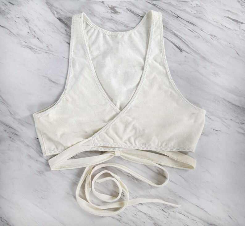 Peut inclure: Soutien-gorge blanc de style enveloppant avec des bretelles r&eacute;glables. Le soutien-gorge est fait d'un tissu doux et extensible et pr&eacute;sente un design crois&eacute; &agrave; l'avant.