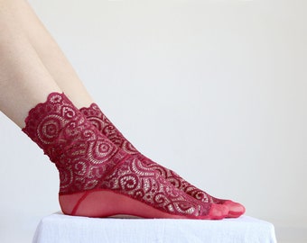 Puede incluir: Un par de calcetines de encaje de tobillo rojos con un delicado patrón floral.