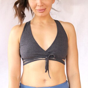 May include: A grey wrap-style sports bra with a criss-cross design at the front. The bra is tied at the centre with a bow.