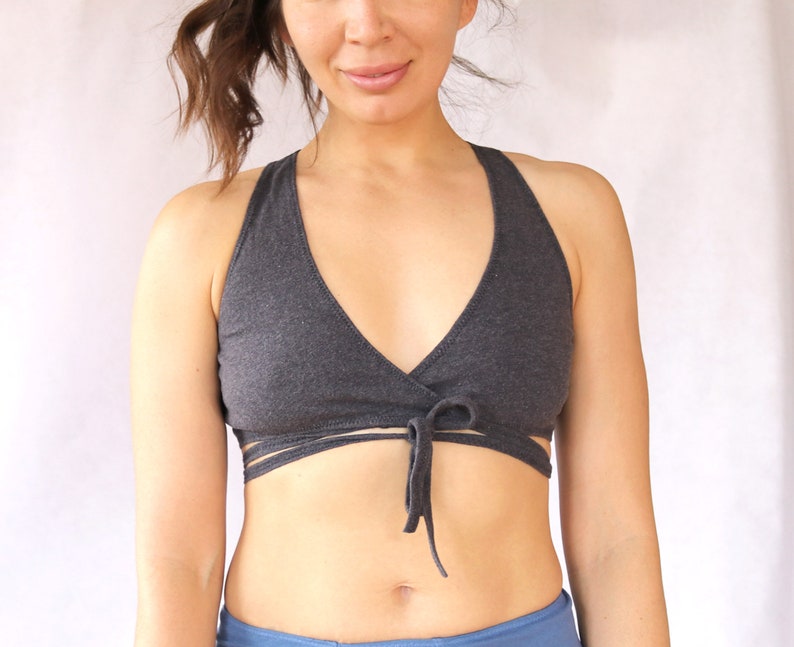 May include: A grey wrap-style sports bra with a criss-cross design at the front. The bra is tied at the centre with a bow.