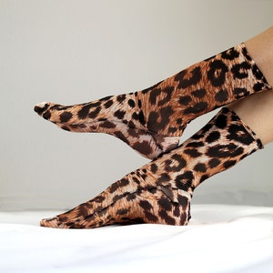 May include: A pair of sheer socks with a leopard print pattern. The socks are brown and black with a mesh-like texture.