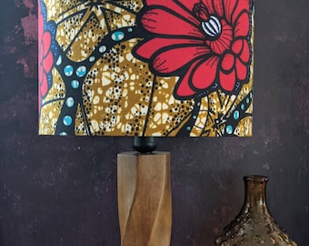 May include: A wooden table lamp with a twisted base and a colorful floral lampshade. The lampshade features a red flower with yellow and blue accents on a brown background.