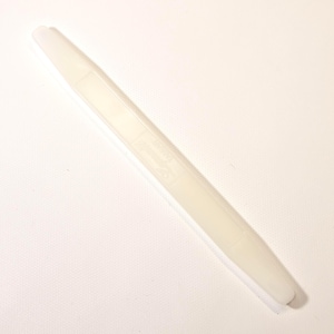 May include: A long, off-white plastic bone folder tool. The tool has a rectangular section with text and a logo. The bone folder is used for smoothing paper and creating crisp folds in various craft projects.
