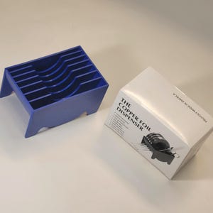 May include: A blue plastic dispenser for copper foil. The dispenser is empty and has 10 slots. The box for the dispenser is white with black text that reads "The Copper Foil Dispenser" and lists features such as "Convenient", "Lightweight", "Durable", "Easy to Use", and "Made in America".