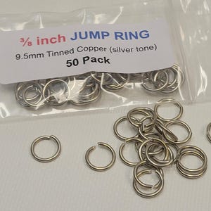 May include: A bag of 50 silver-toned jump rings, made of tinned copper. The rings are 3/8 inch (9.5mm) in diameter. The bag has a label that reads "3/8 inch JUMP RING 9.5mm Tinned Copper (silver tone) 50 Pack".