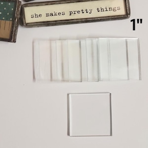 May include: A set of clear glass tiles, some with a frosted finish, and a single square tile. The tiles are arranged in a row and a single tile is below the row. The tiles are 1 inch in size.