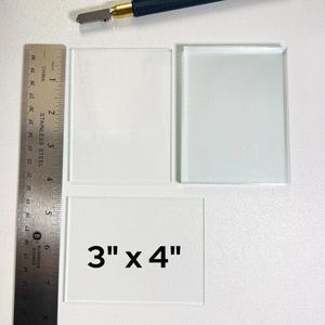 May include: Two clear glass squares, one measuring 3 inches by 4 inches, the other measuring 4 inches by 4 inches. The smaller square has the dimensions printed on it.