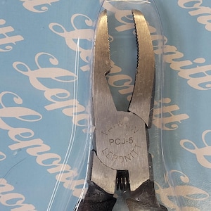 May include: Silver-toned pliers with black handles. The pliers have a circular label that reads "Taiwan PCJ-5 LEPONITT".