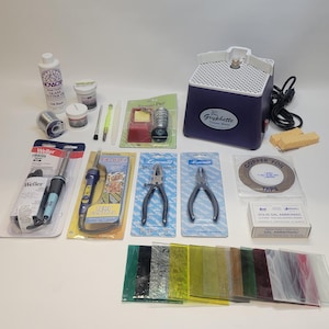 May include: A collection of stained glass supplies including a glass cutter, soldering iron, pliers, copper foil, flux, solder, and a variety of colored glass pieces.