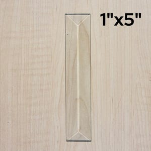 May include: A 1" x 5" wooden panel with a raised, triangular design. The panel is light brown in color and has a smooth surface.