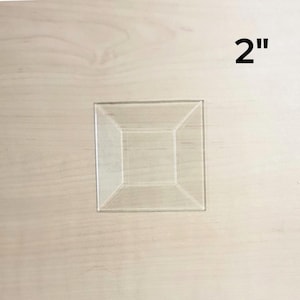 May include: A clear plastic 2-inch square with a raised, beveled edge.